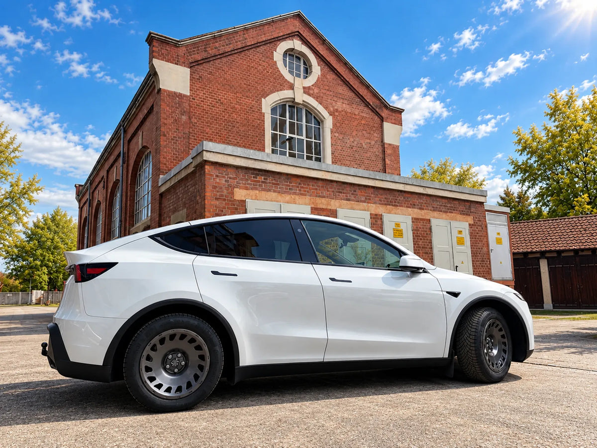 Tesla Model Y Juniper mit Erion 10 Kompletträdern 18 Zoll in der Seitenansicht vor Backsteinhalle