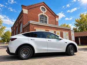Tesla Model Y Juniper mit Erion 10 Kompletträdern 18 Zoll in der Seitenansicht vor Backsteinhalle